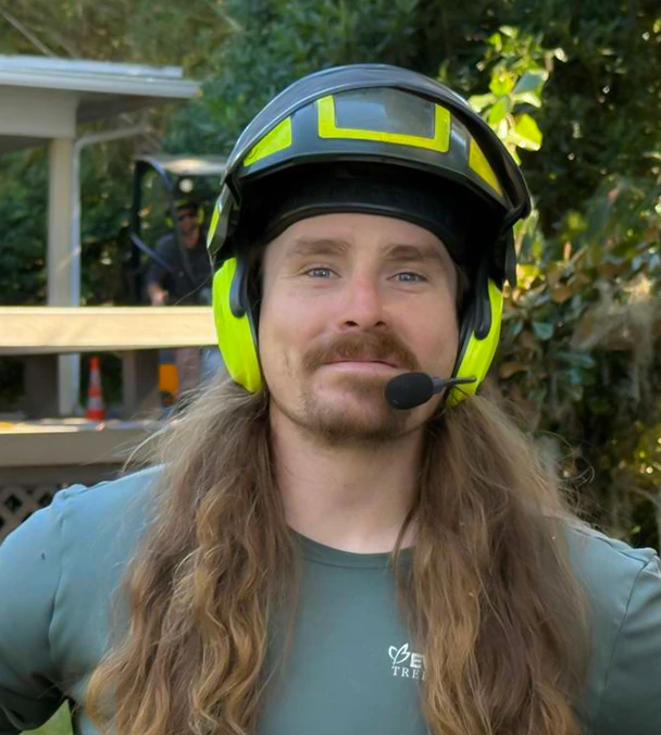 Kyle Sullivan, Evergreen Tree Company crew member wearing safety gear, smiling on site.